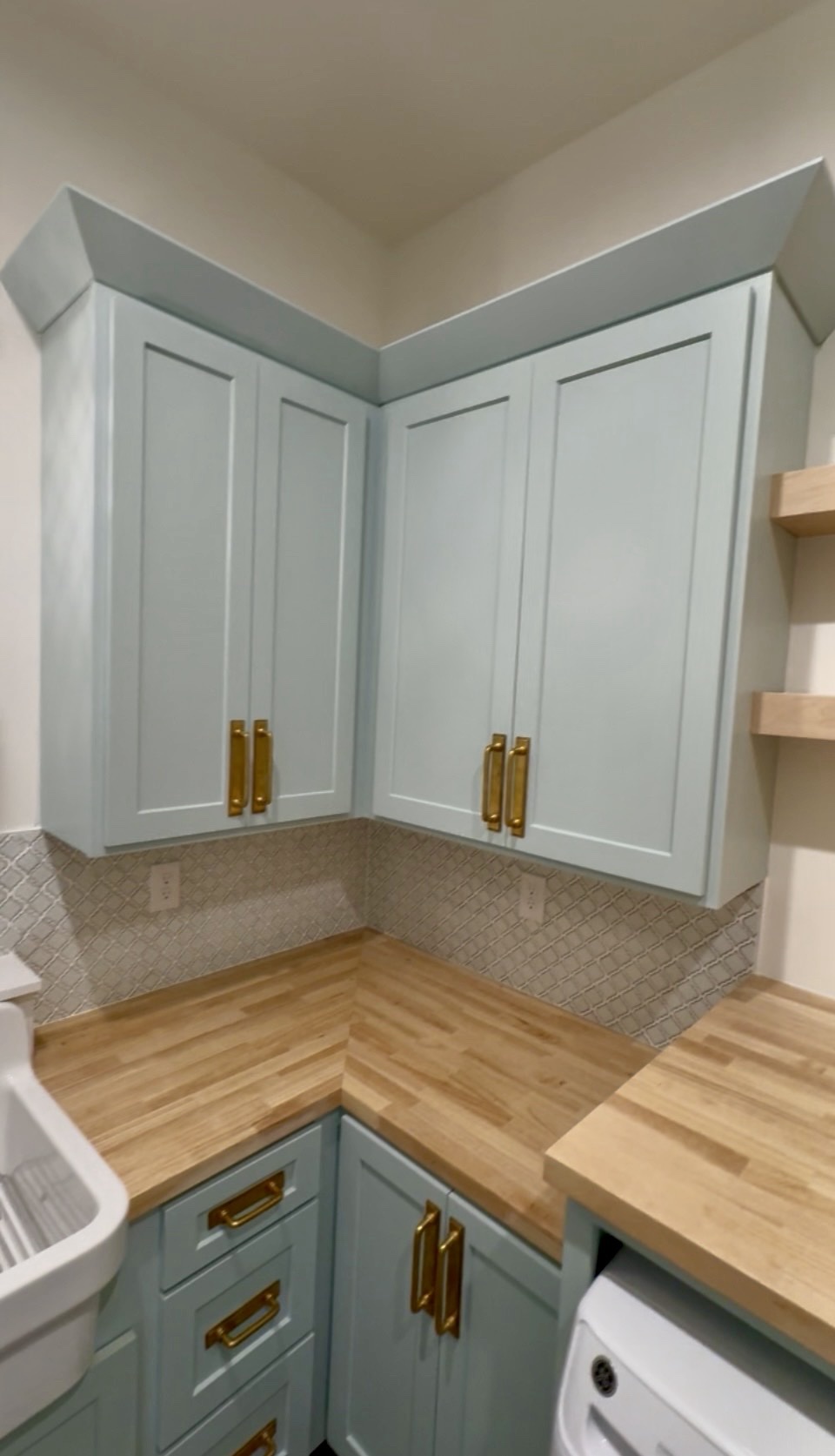 Dream laundry room with sage shaker cabinets and brass hardware